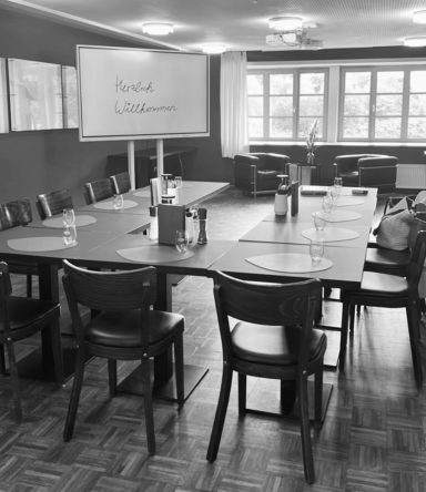 HR Seminare und Business Coaching About Work GmbH Konferenzraum mit einem langen Tisch, Stühlen und großen Fenstern im Hintergrund.