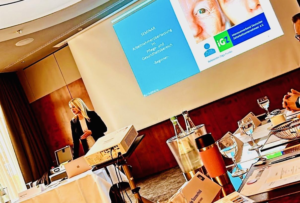 Olga Punko Dozentin About Work GmbH „Seminarleitung hält Vortrag über Arbeitnehmerüberlassung im Pflege- und Gesundheitsbereich – Schulungssituation mit Präsentation.“